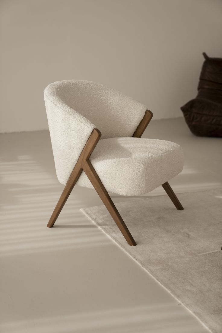 Mid-century modern accent chair with ivory cream bouclé fabric upholstery and a sculptural walnut wood scissor-leg frame.