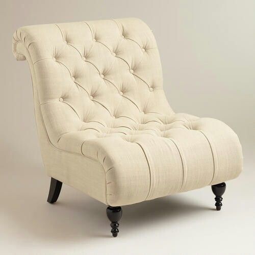 ivory button tufted slipper chair with rolled back and dark turned wooden legs on studio background