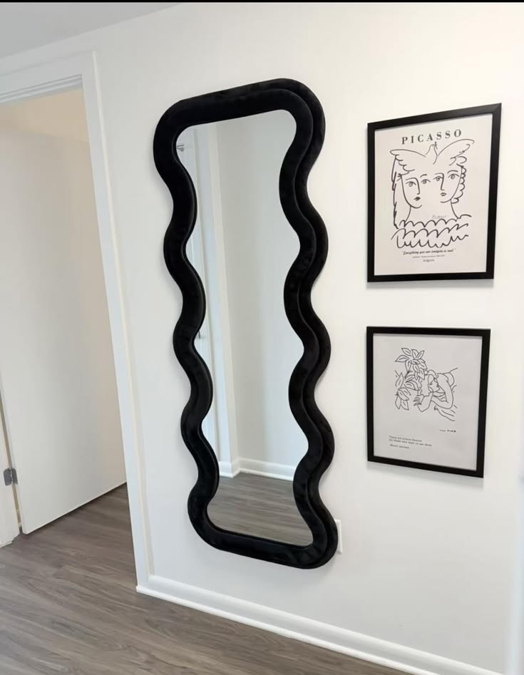 Onyx postmodern full-length wall mirror featuring a plush black velvet wavy frame mounted next to framed Picasso line art.