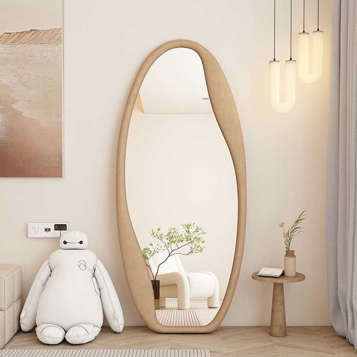Kova organic asymmetrical full-length floor mirror with a beige textured frame leaning against a wall in a bright minimalist room.