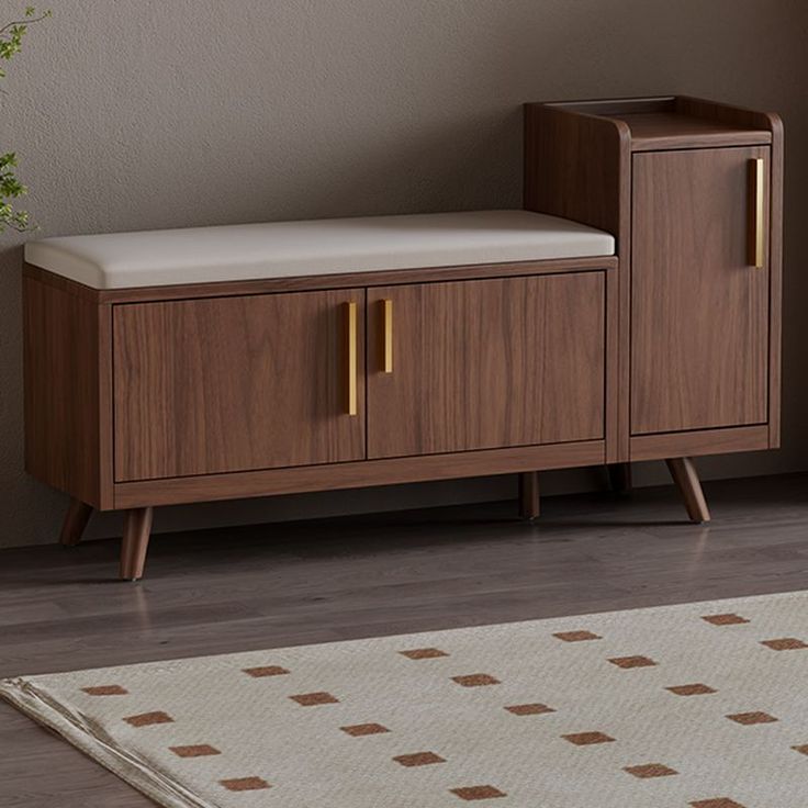 Jamson mid-century walnut wood entryway shoe storage bench featuring a cream padded seat cushion and vertical brass handle pulls.