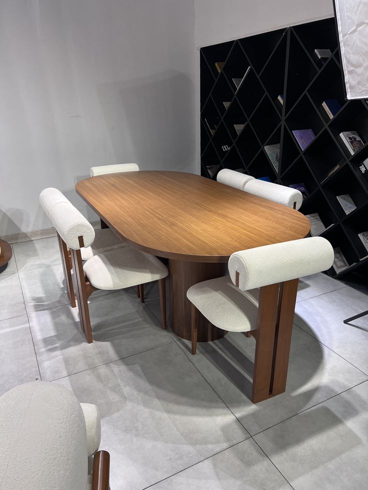 A modern oval oak dining table with dual fluted pedestal bases, surrounded by six upholstered wood-framed chairs in a styled dining room.