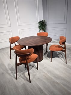 A mid-century round dark walnut dining table with a fluted pedestal base surrounded by four burnt orange upholstered wood chairs.