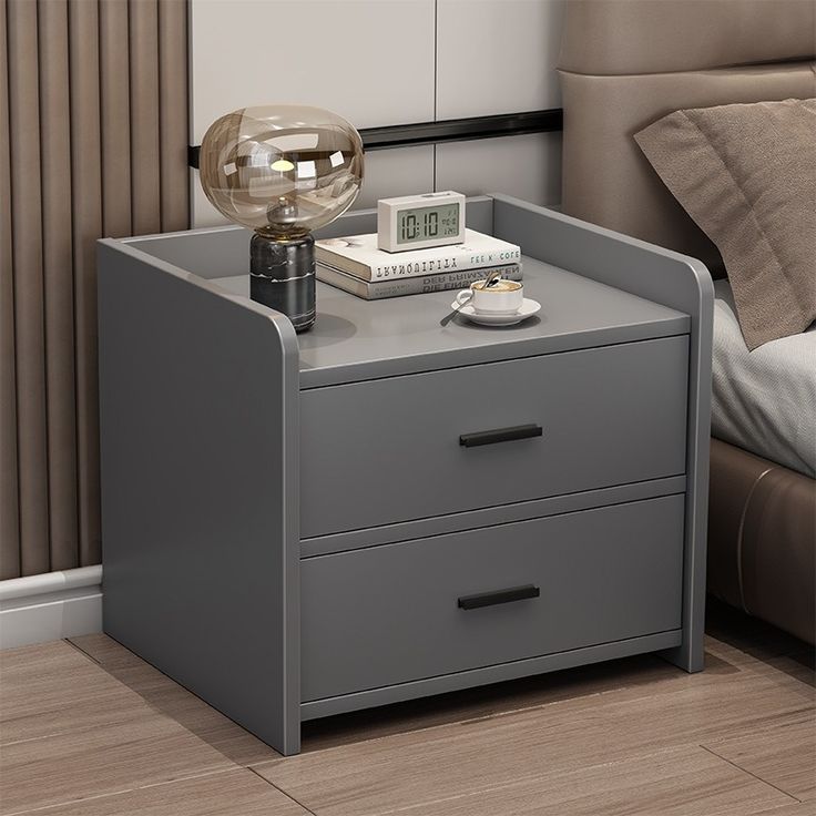 Silas modern dark grey nightstand with two drawers and black pull bars styled next to a brown leather bed frame.