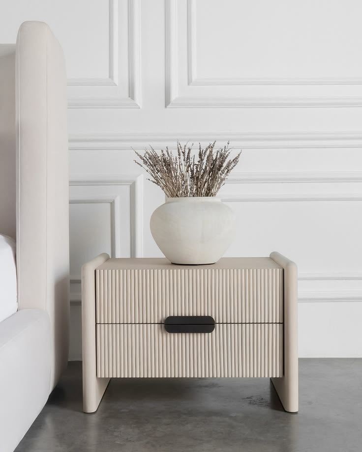 Luxury Soreli Oak Nightstand featuring a warm white fluted front with two drawers and a black pill-shaped pull handle in a bright bedroom setting.